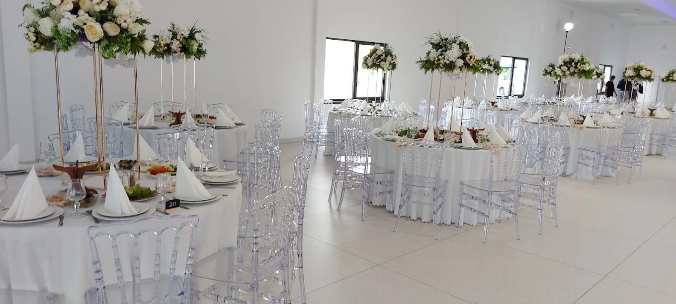 Salle de réception avec tables décorées et chaises transparentes